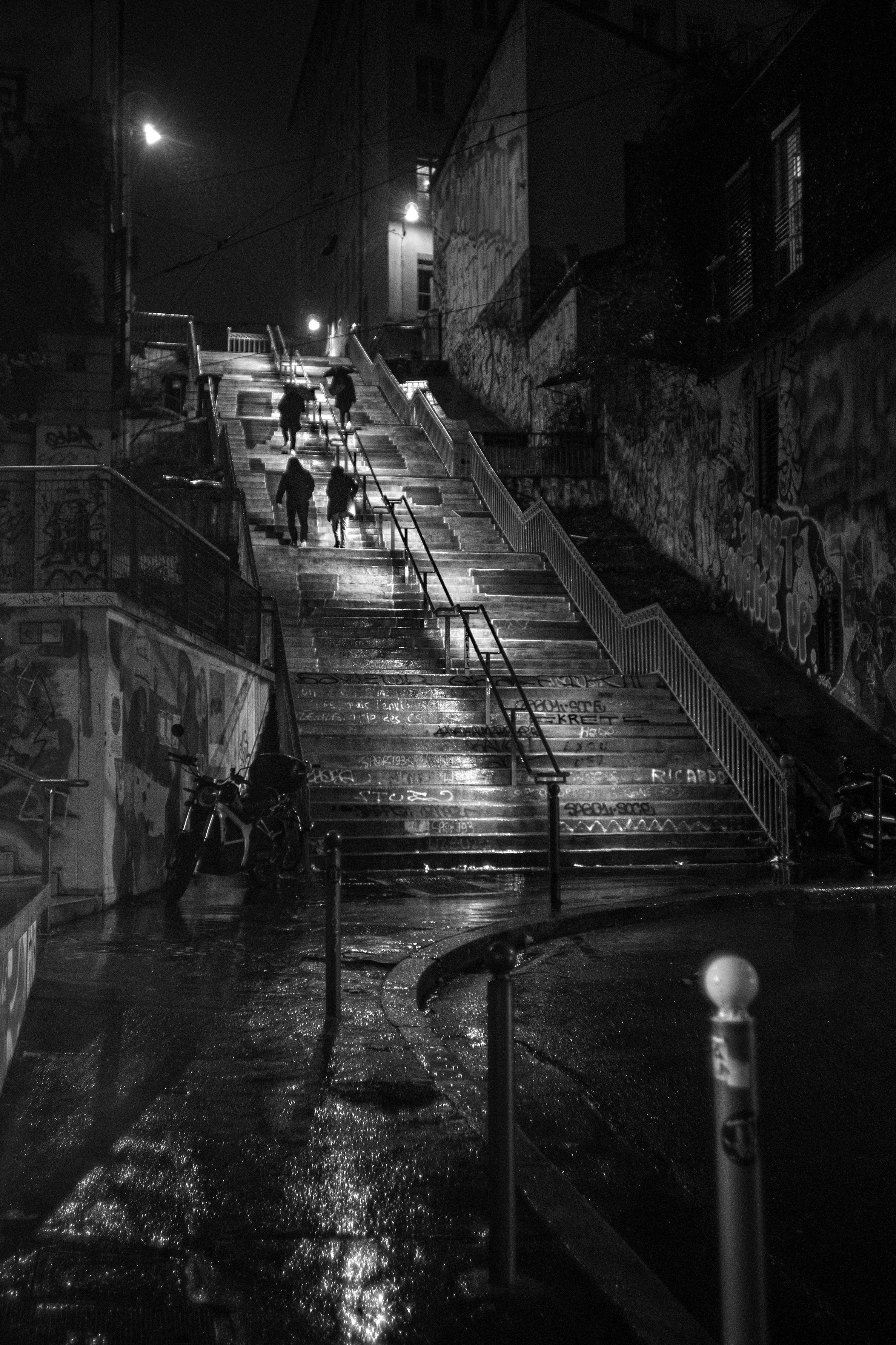 A rainy night staircase, figures climbing