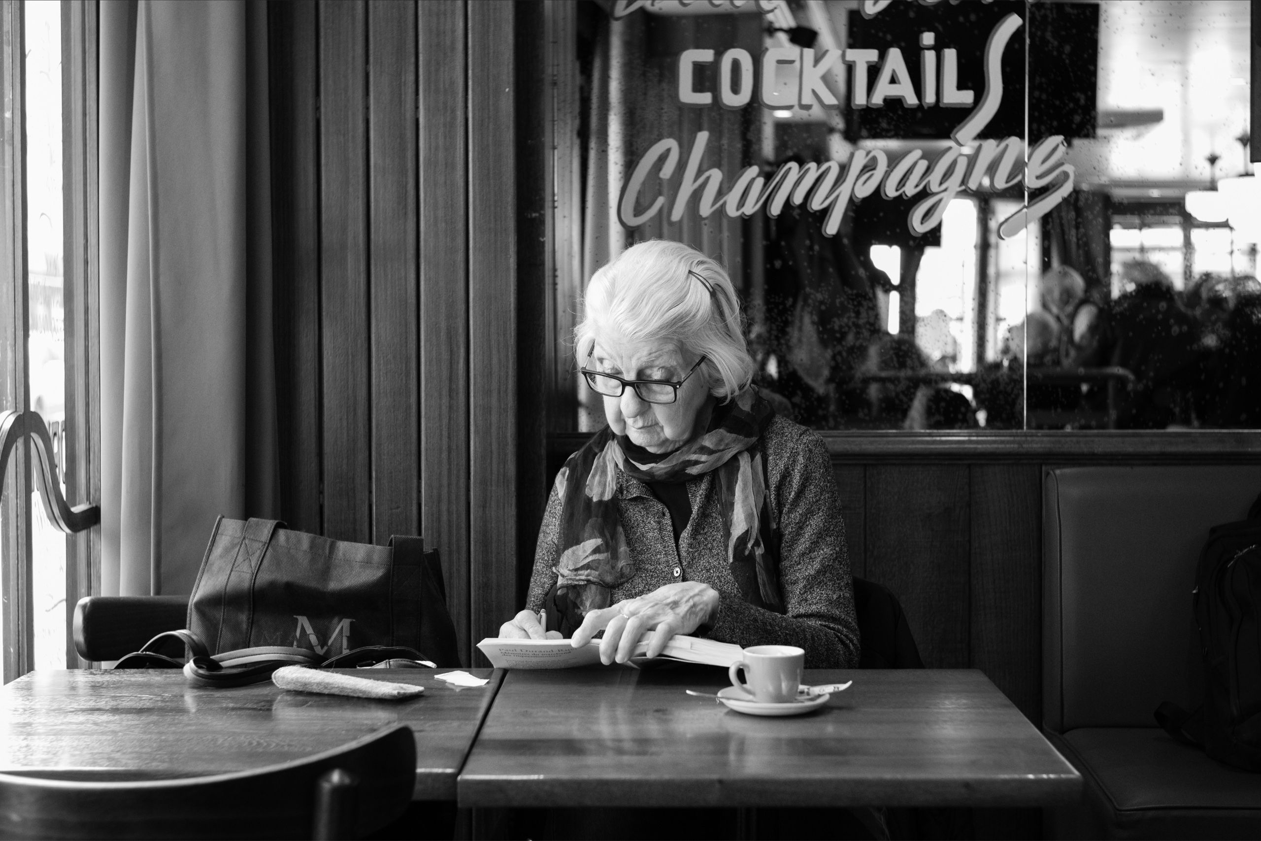 An elderly woman writing in a Paris café