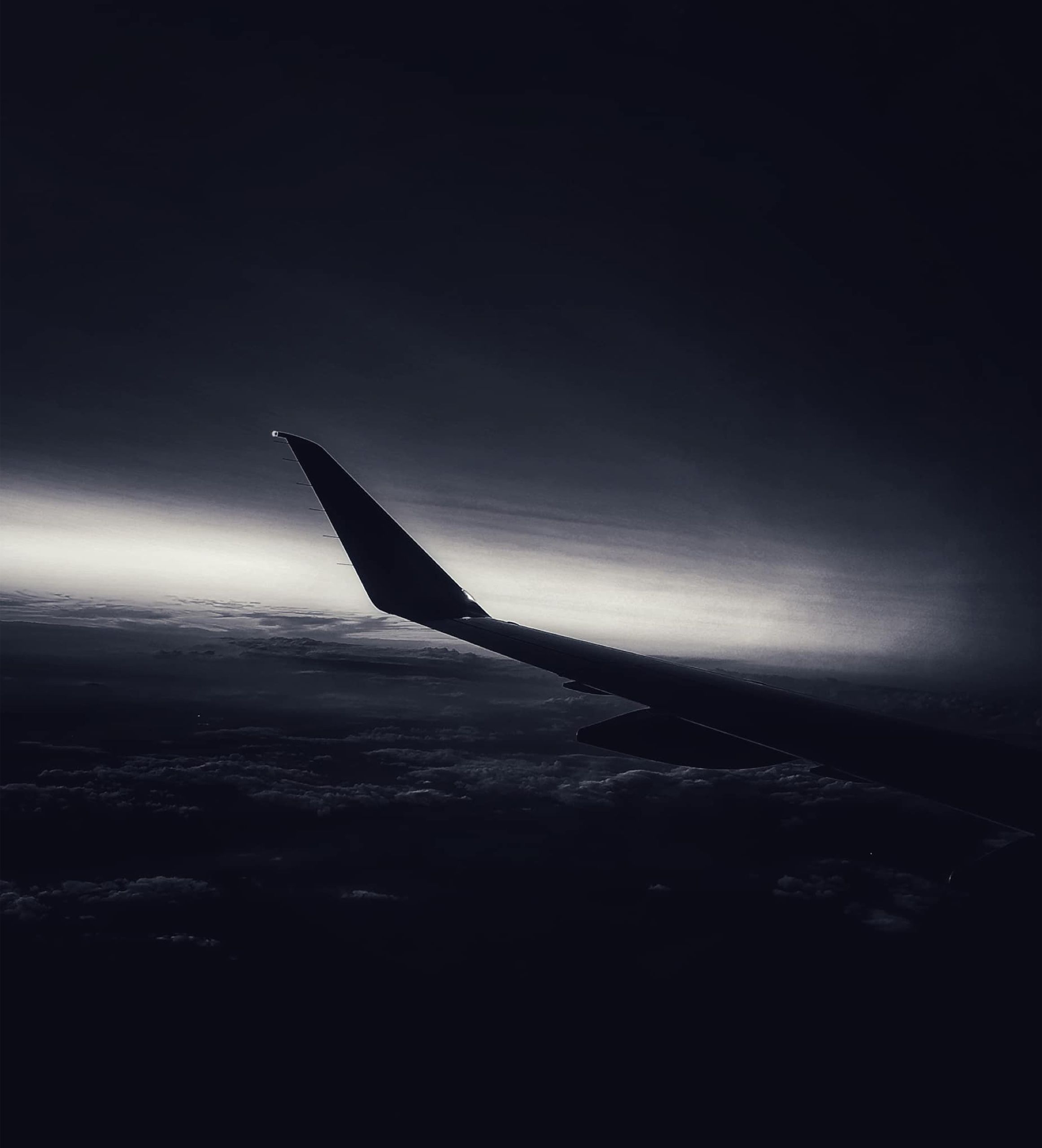 An aircraft wing over a dark horizon